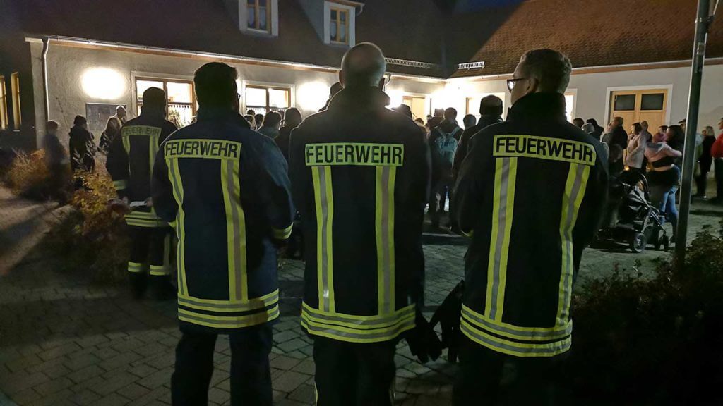 Bild: drei Feuerwehrmänner nebeneinander gezeigt von hinten